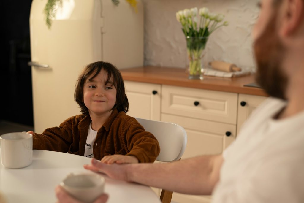 Niño conversando con un adulto en la mesa de la cocina