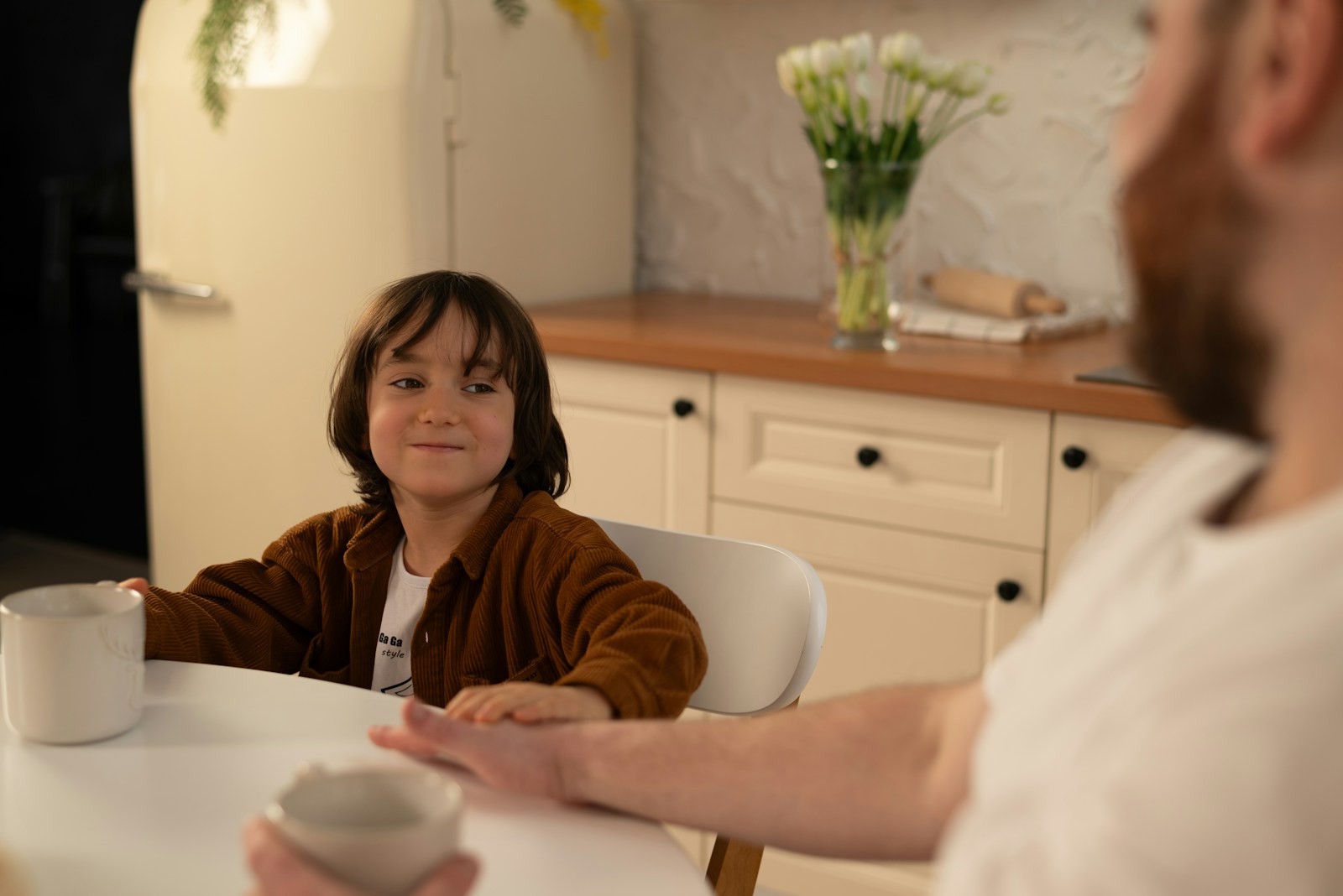 Niño conversando con un adulto en la mesa de la cocina