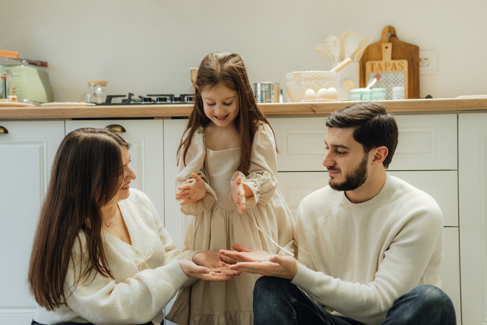 Madre, padre y niña compartiendo un momento en la cocina